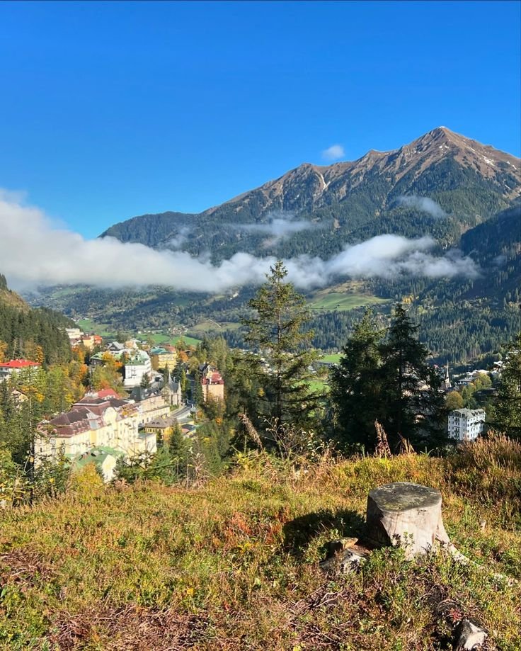 This may contain: the mountains are covered with clouds and trees in the foreground is a small town