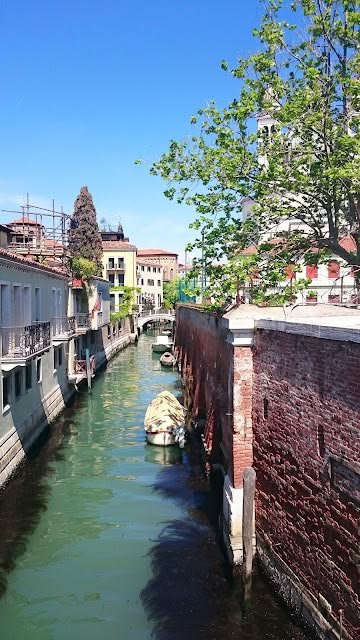 This may contain: a river running through a city with tall buildings on both sides and green water in the middle