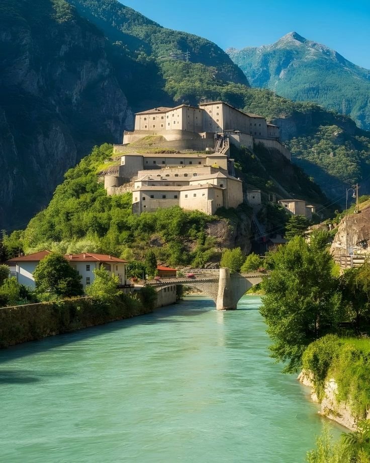 This may contain: an old castle perched on top of a hill next to a river in the mountains