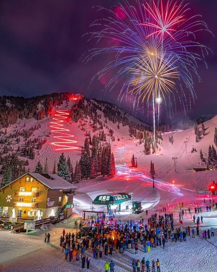 This may contain: fireworks are lit up the sky above a ski resort