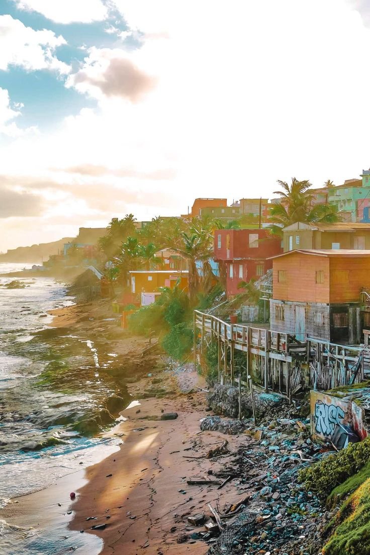 This may contain: the beach is littered with trash and old wooden buildings on it's shore line