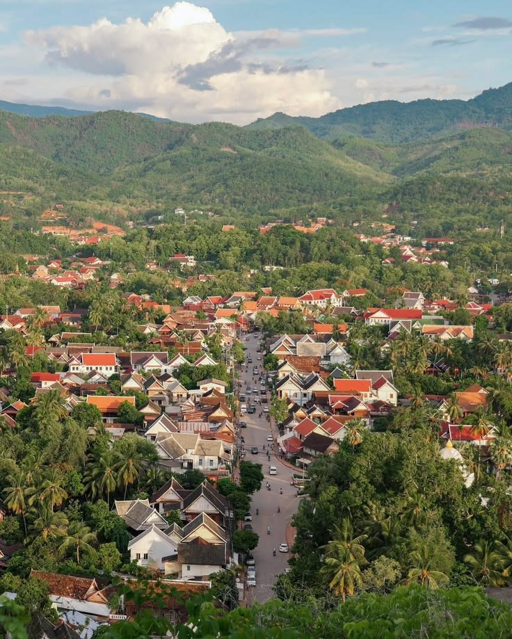 This may contain: an aerial view of a small town surrounded by trees and mountains in the distance,