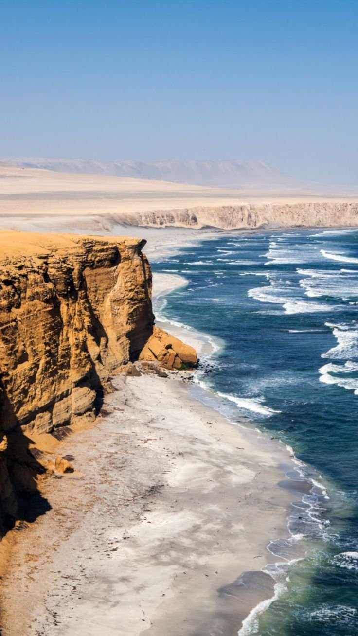 This may contain: the beach is next to some cliffs and water
