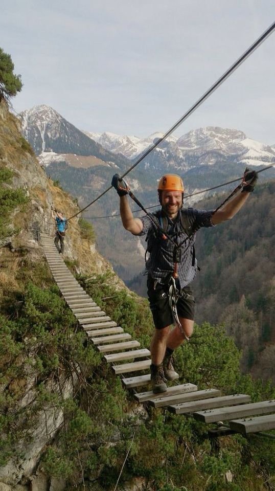 This may contain: a man walking across a wooden bridge on top of a mountain