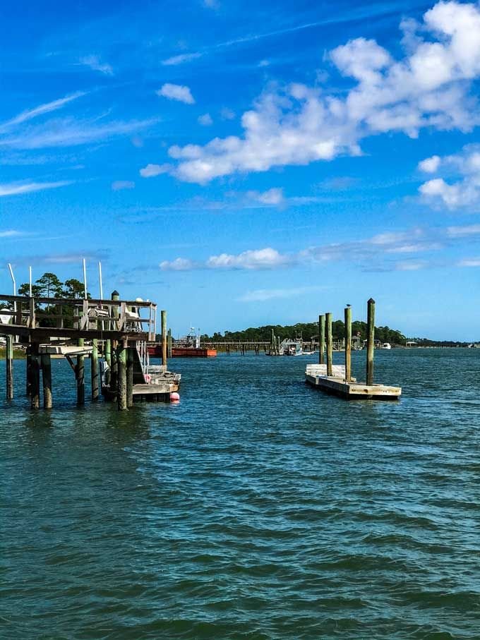 This may contain: two boats floating on top of a body of water next to a wooden pier under a cloudy blue sky