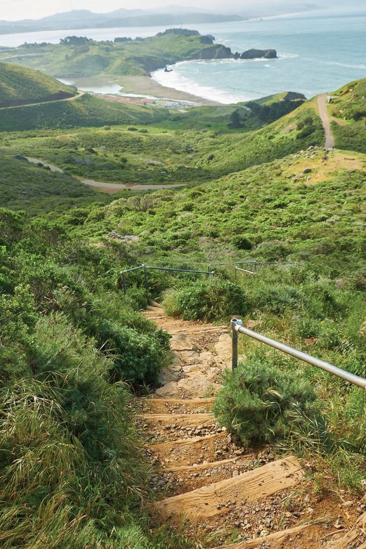 This may contain: a path leading up to the ocean with green hills in the background