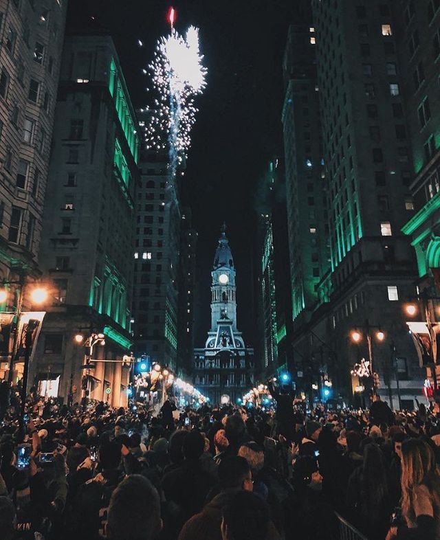 This may contain: a large group of people standing in the middle of a street at night with fireworks