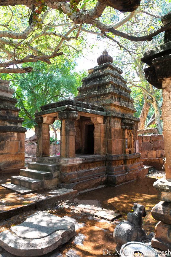 This may contain: an old stone structure in the middle of a tree filled area with statues and trees