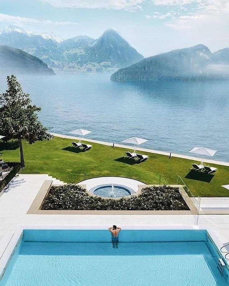 This may contain: a person sitting on the edge of a swimming pool in front of an ocean view