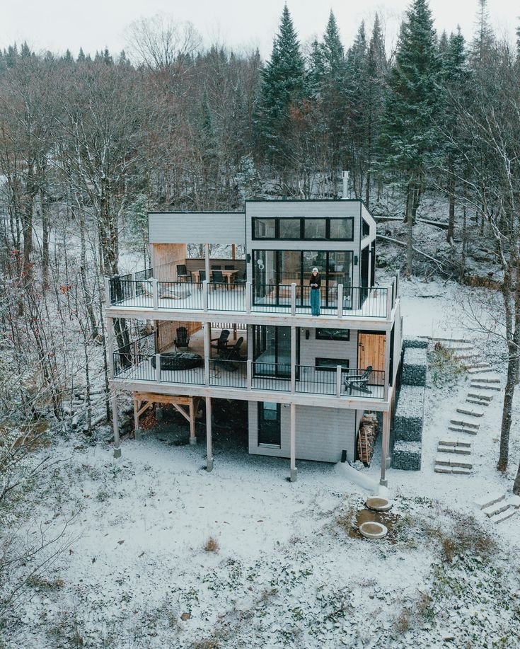 This may contain: an aerial view of a house surrounded by trees in the middle of winter with snow on the ground
