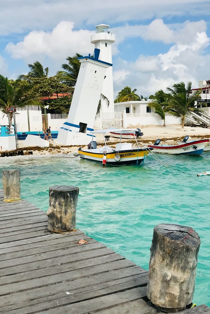 This may contain: boats in the water near a pier with a light house on it's side