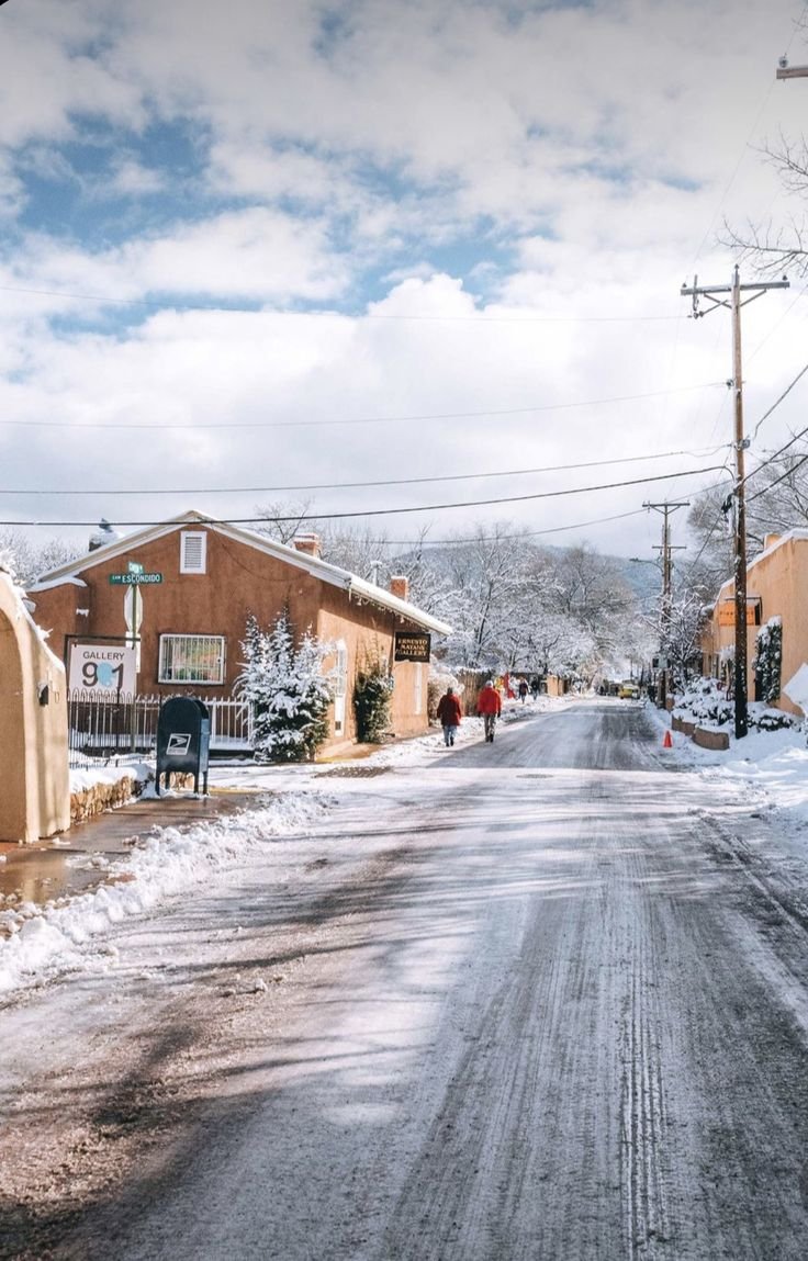 This may contain: a street with snow on the ground and houses in the background