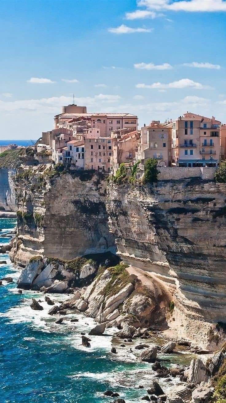 This may contain: the city is perched on top of a cliff overlooking the ocean and cliffs that surround it