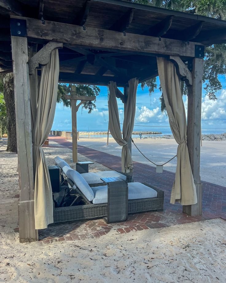 This may contain: a gazebo on the beach with two lounge chairs under it