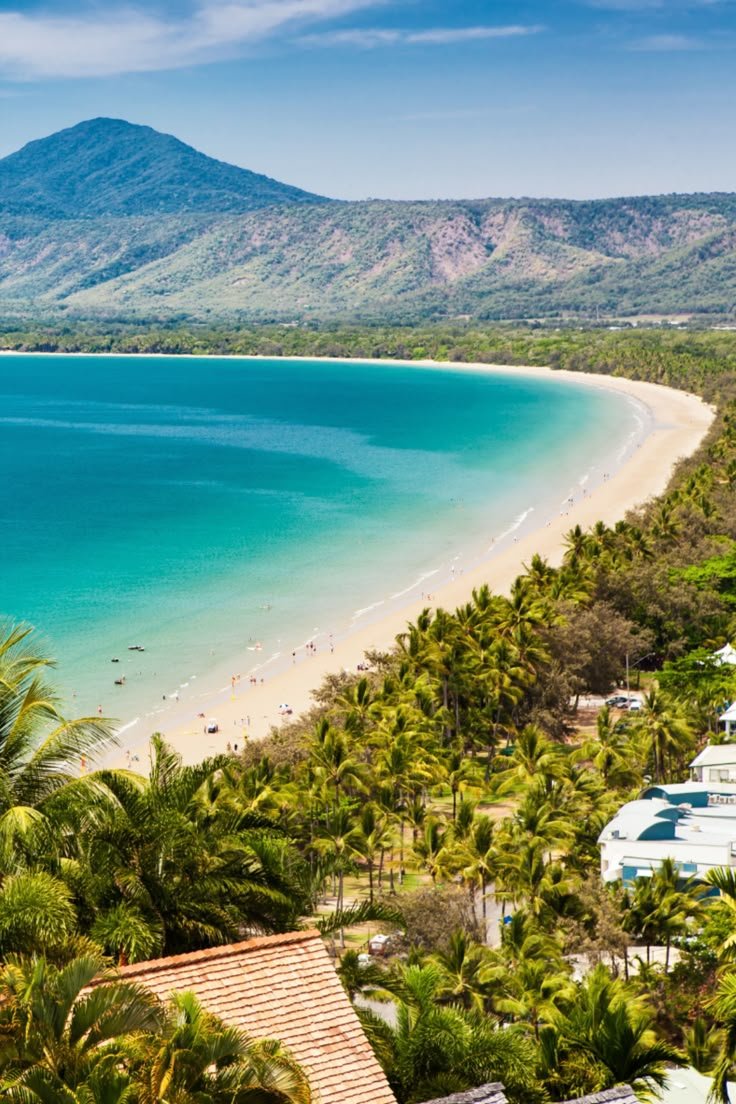 This may contain: the beach is surrounded by palm trees and blue water, with mountains in the background