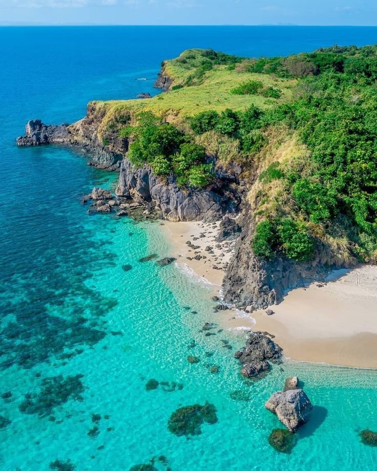 This may contain: an aerial view of the beach and ocean in front of some cliffs with trees on top