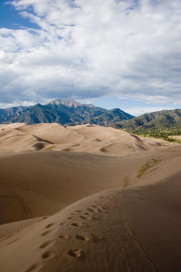This may contain: sand dunes with mountains in the background