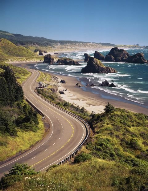 This may contain: an empty road near the ocean on a sunny day
