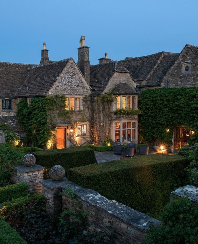 This may contain: a large house with lots of ivy growing on it's walls and windows at night