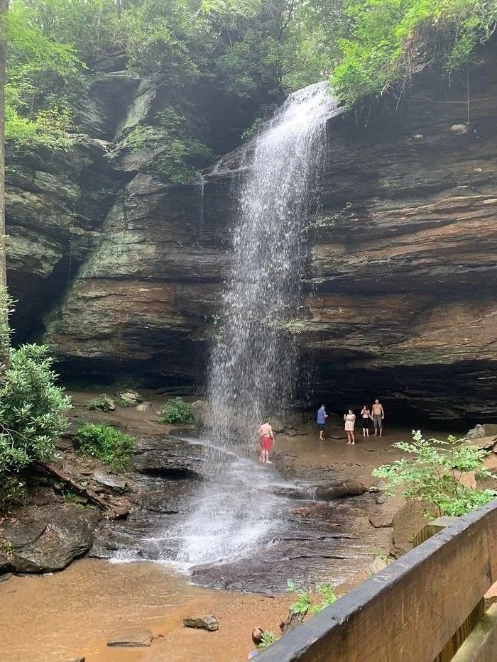 This may contain: people are standing at the base of a waterfall
