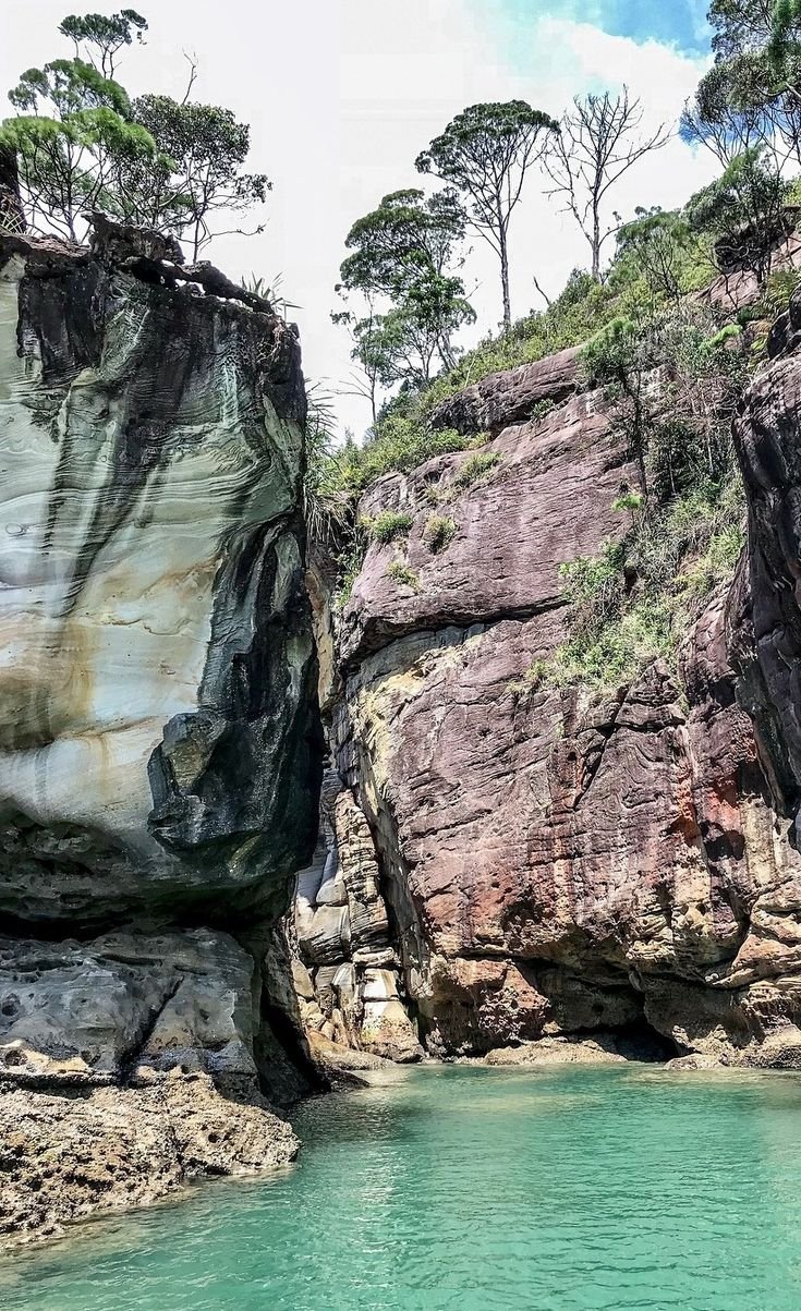 This may contain: the water is crystal blue and green in this rocky area with some trees on top