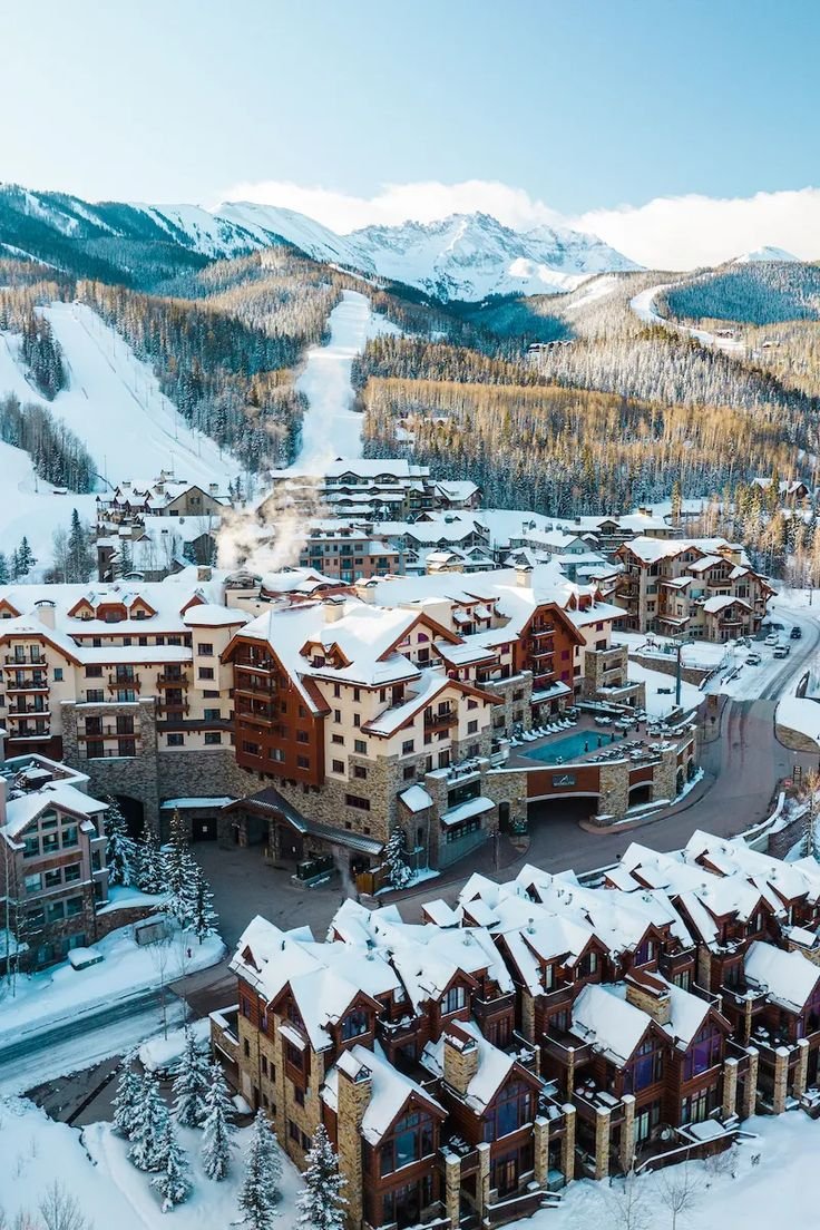 This may contain: an aerial view of a ski resort in the mountains with snow on the ground and trees