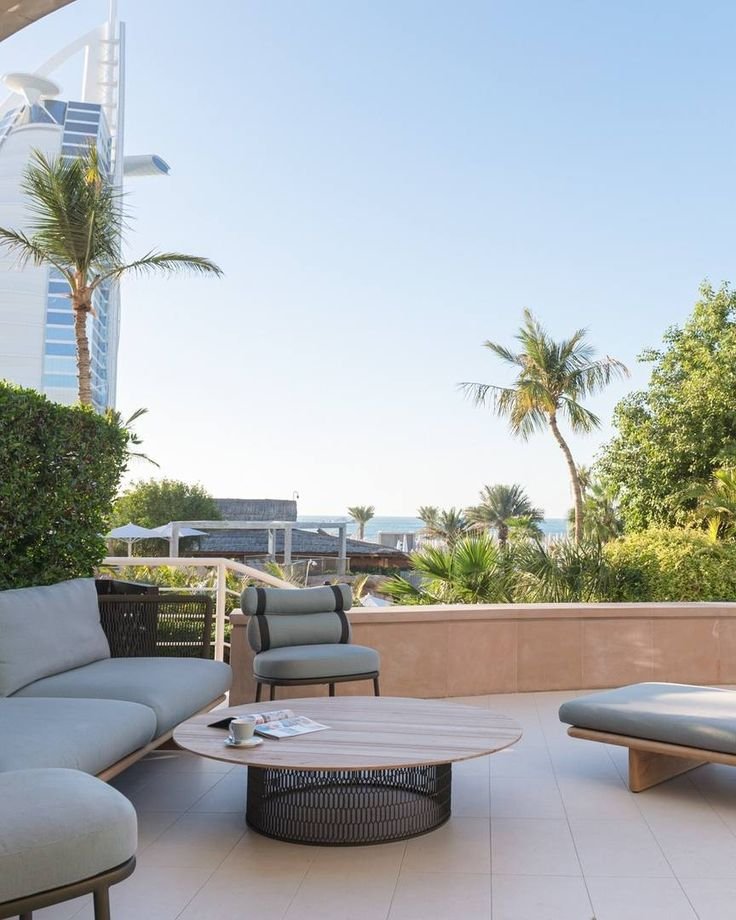 This may contain: an outdoor living area with couches, tables and palm trees in the back ground