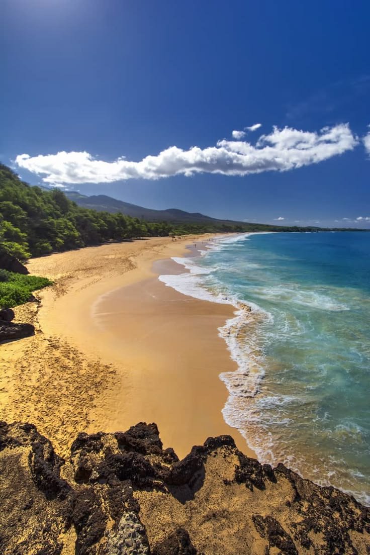 This may contain: the beach is sandy and clear with waves coming in from the ocean on a sunny day
