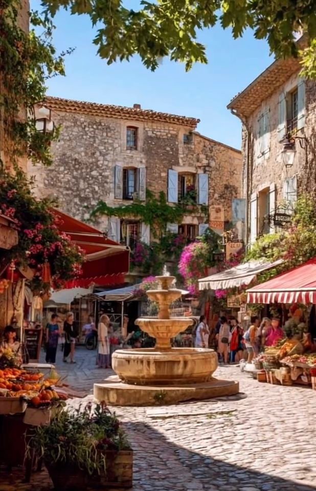 This may contain: an outdoor market with lots of people walking around and shops on the side of it