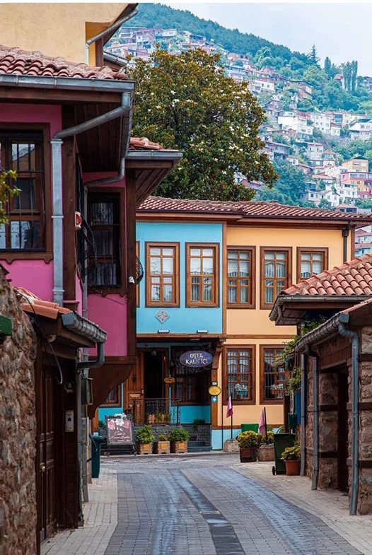 This may contain: an empty street with buildings on both sides and mountains in the background
