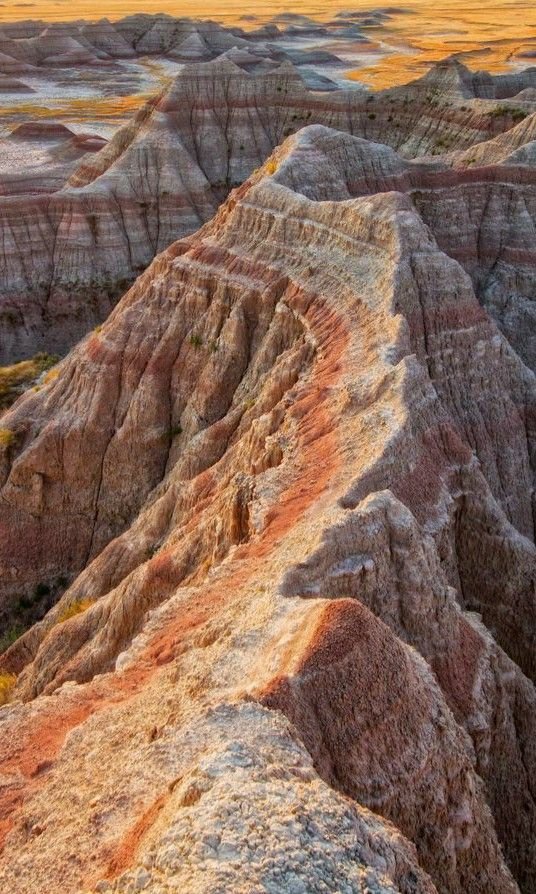 This may contain: the sun is setting over badlands and hills