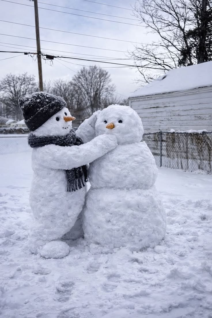This may contain: two snowmen standing next to each other with their arms around one another in the snow