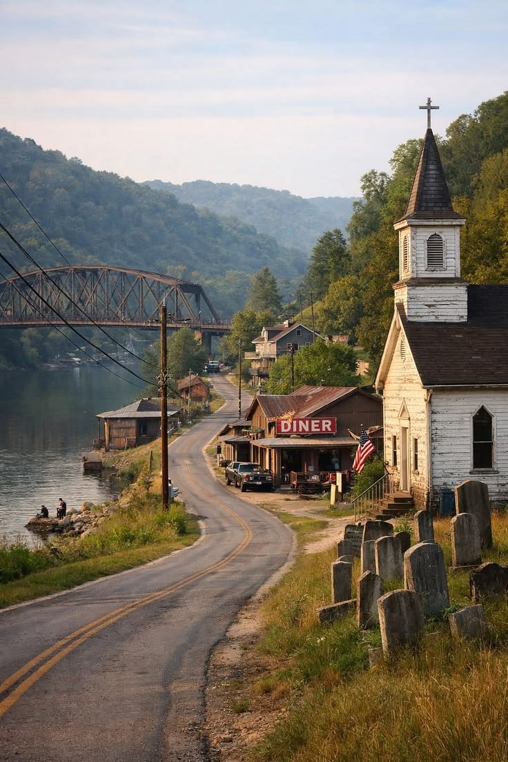 This may contain: an old church sits on the side of a road next to a body of water