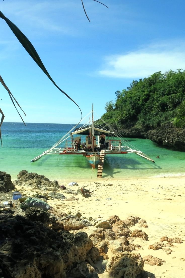 This may contain: a boat that is floating in the water near some rocks and sand on a beach