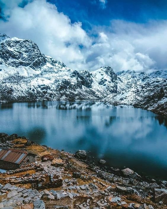This may contain: a mountain lake surrounded by snow covered mountains