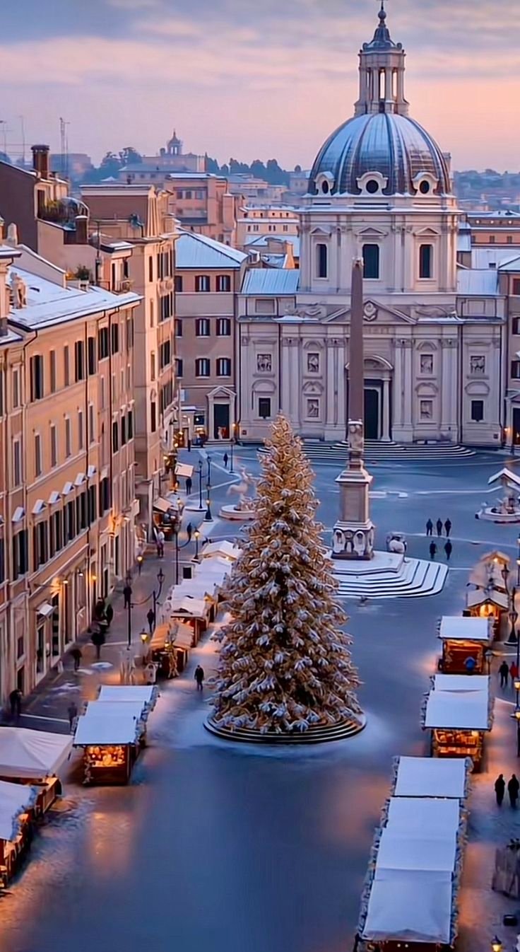 This may contain: a christmas tree is in the middle of a plaza with many buildings and trees around it