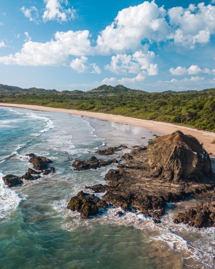 This may contain: an aerial view of the beach and ocean with waves crashing on it's shore