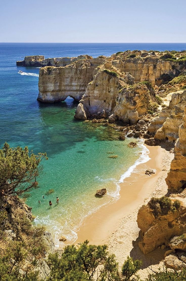 This may contain: people are swimming in the clear blue water near an arch shaped rock formation at the beach