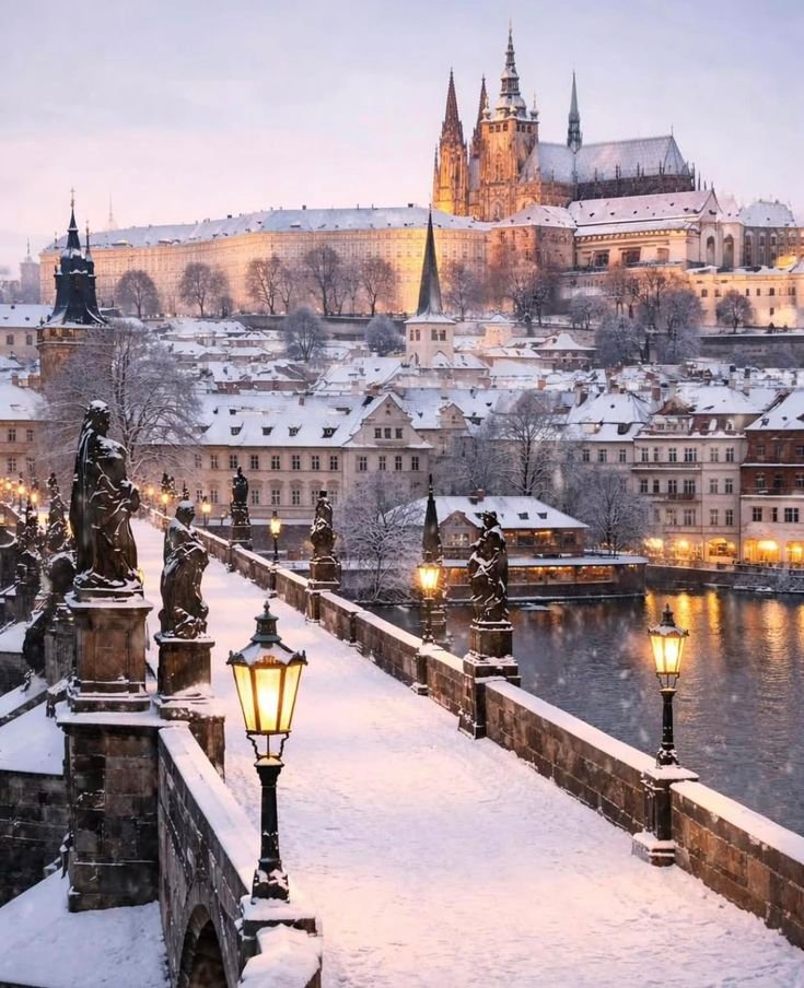 This may contain: a snowy view of a city with buildings and lights in the foreground, and a river running through it