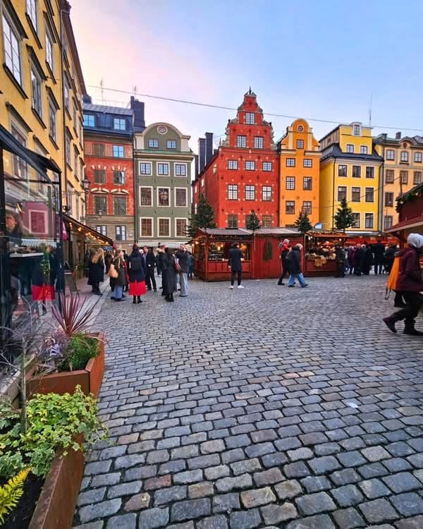 This may contain: people are walking around an outdoor market in the middle of a cobblestone street
