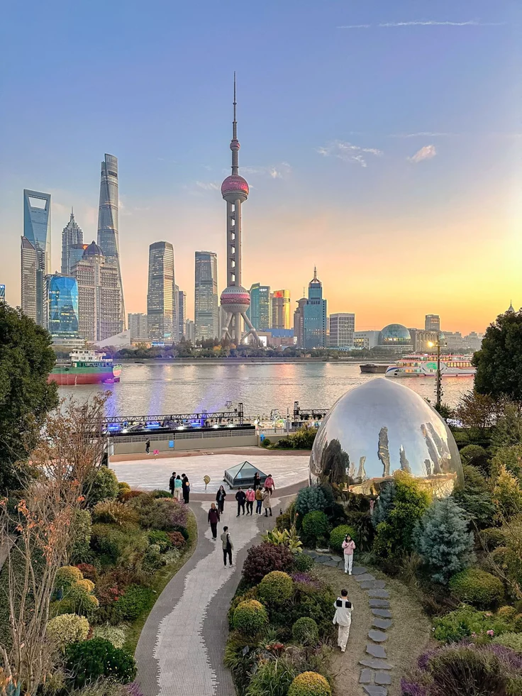 This may contain: people are walking around in front of the water and cityscape with skyscrapers