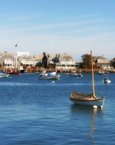 This may contain: a sailboat floating on top of a body of water next to houses in the background