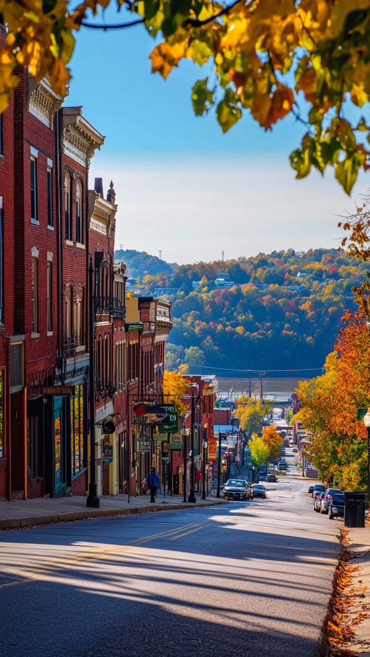 This contains: A charming street in a small town in West Virginia, lined with historic brick buildings and colorful autumn foliage, one of the best places to live in West Virginia.