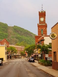 This may contain: a clock tower on the side of a building with cars parked in front of it