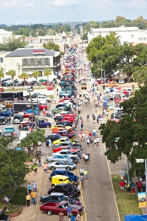 This may contain: an aerial view of a parking lot full of cars and people walking on the sidewalk