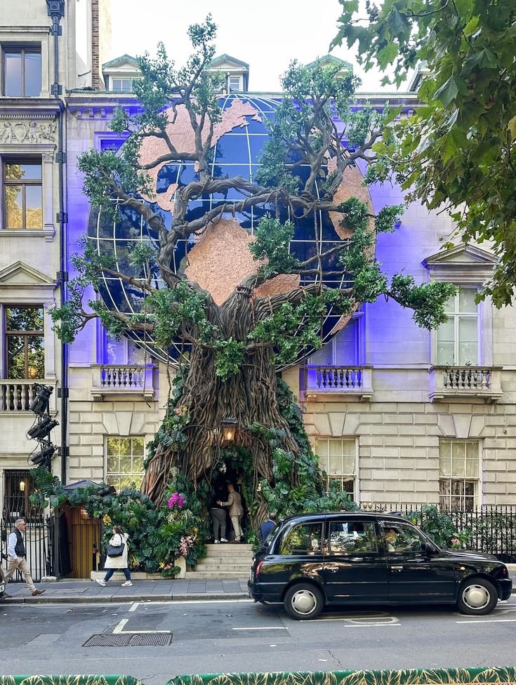 This may contain: a car is parked in front of a building with a tree growing on it's side