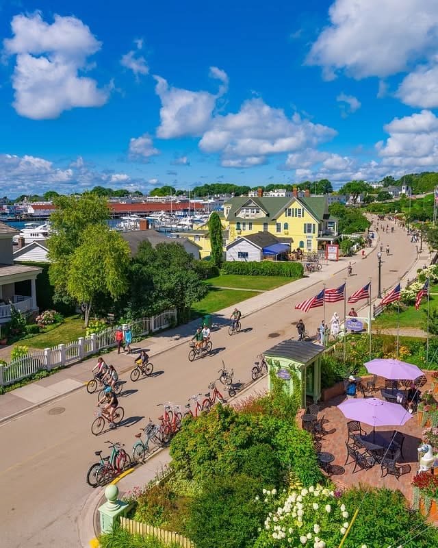 This may contain: an aerial view of people riding bicycles down a street with houses in the back ground