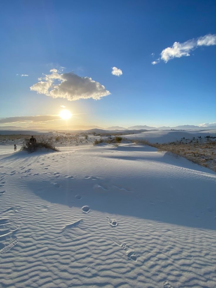 This may contain: the sun shines brightly in the distance over snow covered ground with footprints on it