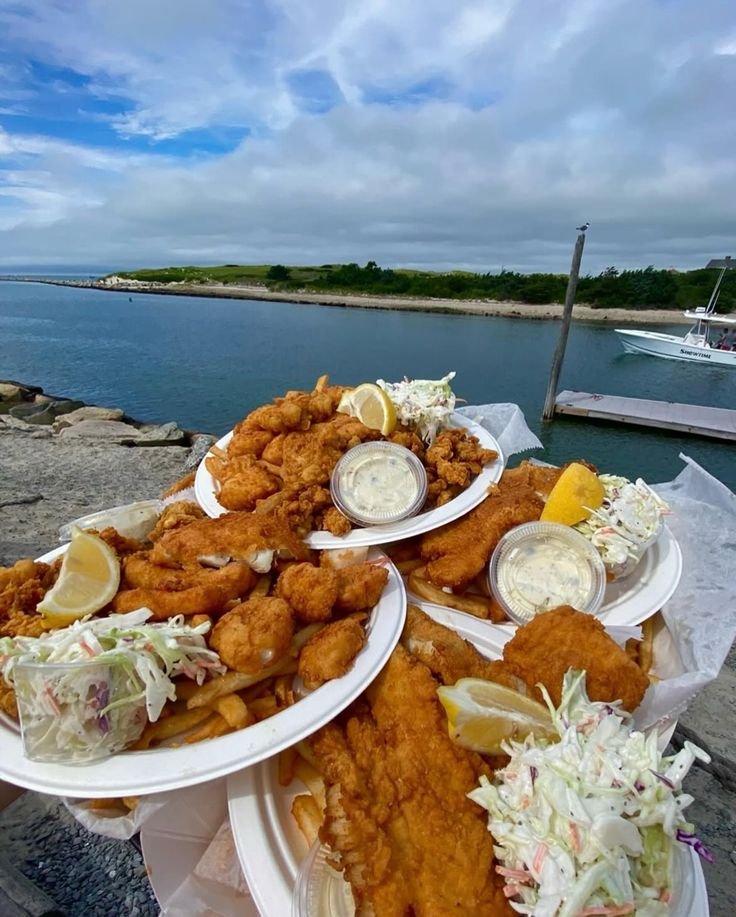 This may contain: several plates of food on a table near the water
