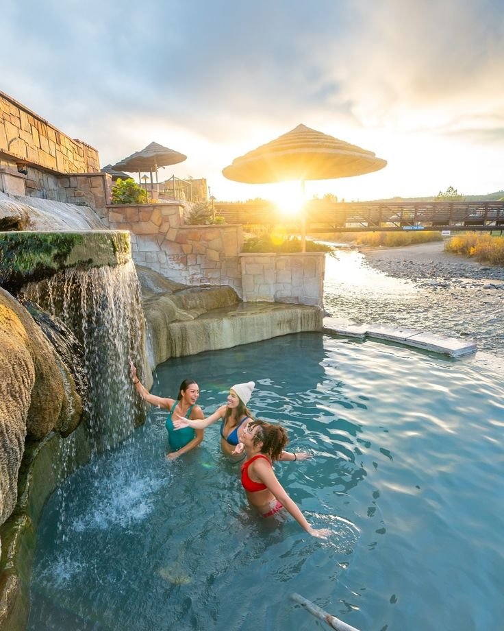 This may contain: three people are playing in the pool at sunset